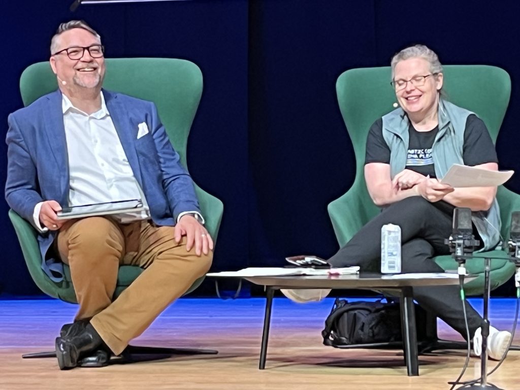 Jason and Lara sitting on stage during the live session, smilling.