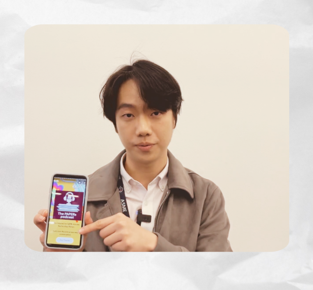 Jun holding up his smartphone that shows Papers podcast on the screen.